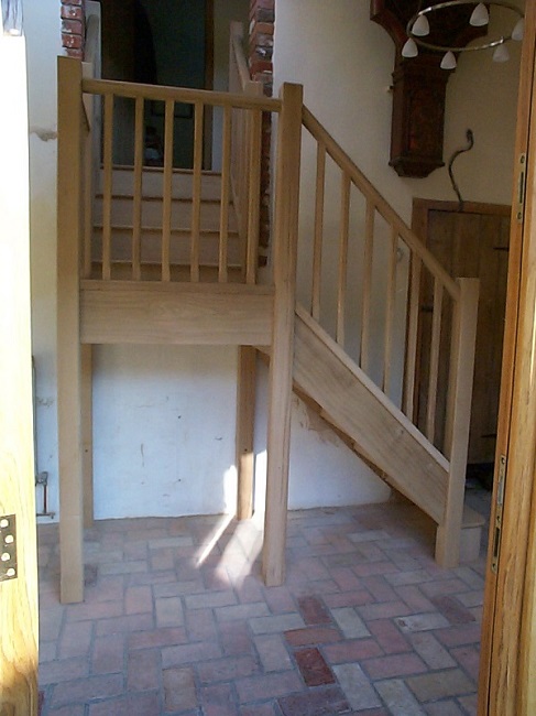 Oak stairs with half landing, stop chamfered newels and spindles. Closed riser and bull nose bottom tread